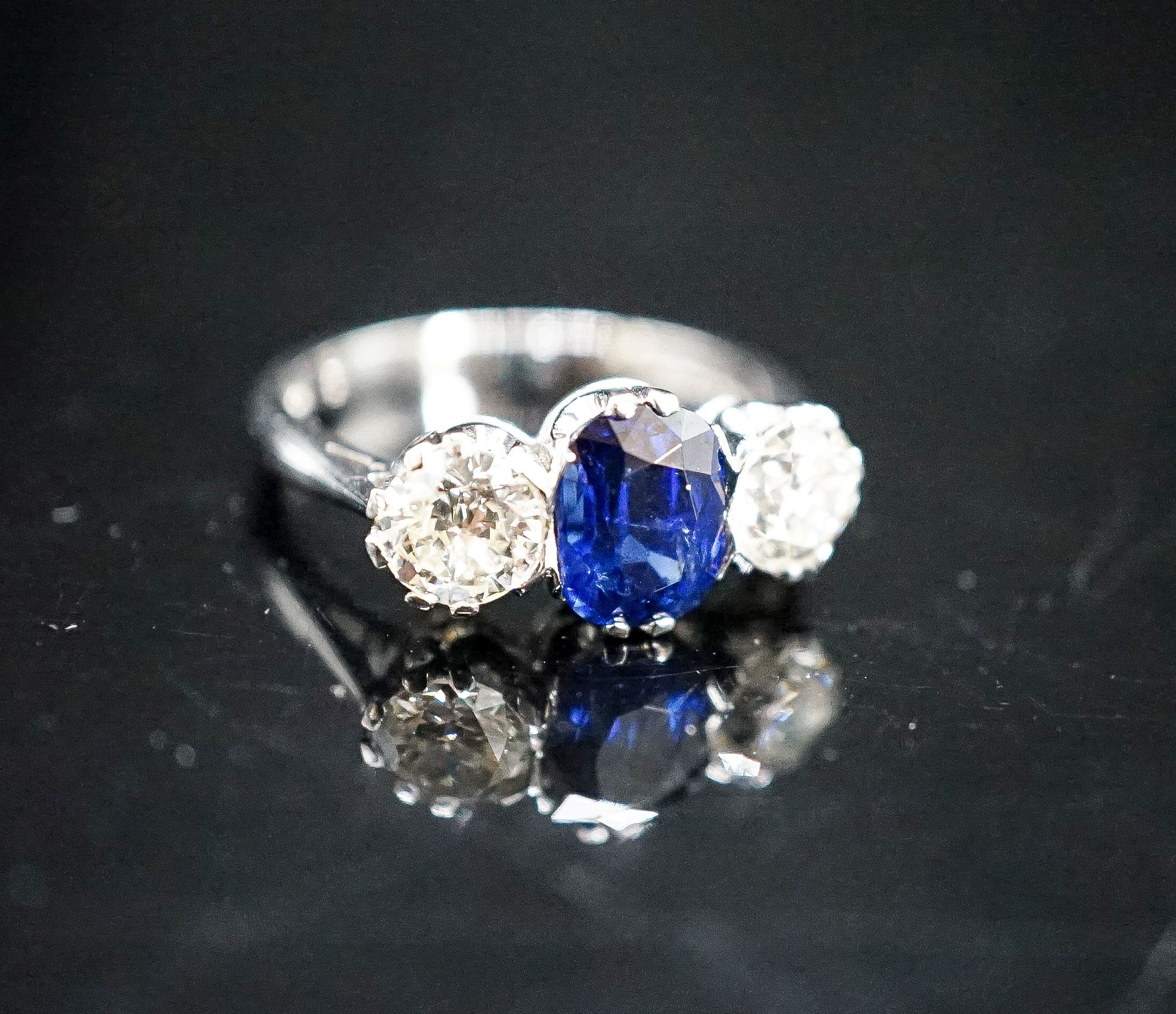 A modern 18ct white gold, single stone sapphire and two stone diamond set ring, size L, gross weight 4.2 grams